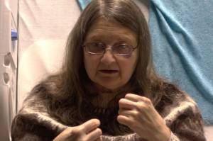 From her hospital bed on Friday, Nov. 24, Christina Florschutz demonstrates how she pulled pajama bottoms that she found in the landslide debris over her legs, arms and head to keep warm. Her house was destroyed in the landslide, and after spending the night in the wreckage, she was rescued the morning of Tuesday, Nov. 21. (Caroleine James / Wrangell Sentinel)