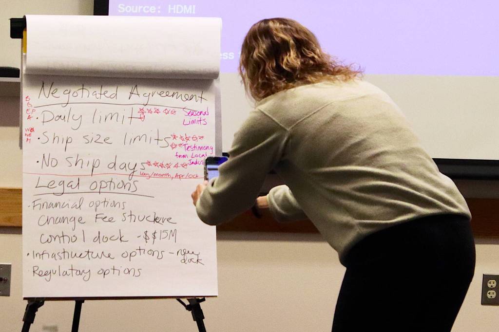 Alexandra Pierce, tourism manager for the City and Borough of Juneau, takes a photo of a list of possible actions to address cruise ship impacts after Assembly members offer their opinions during a retreat Saturday at Juneau International Airport. (Mark Sabbatini / Juneau Empire)