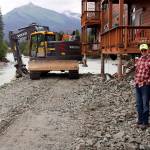 Steve Bradford (left) and Mark Kissel, both vice presidents of the Riverside Condominiums Homeowners Association, discuss repairs to two of the complexs buildings on Aug. 9 as a bulldozer places rock fill under a corner of one building exposed by erosion during record flooding of the Mendenhall River on Aug. 5. Repairs to both buildings ultimately were successful. (Mark Sabbatini / Juneau Empire file photo)