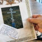 George Kudrin holds a photo of his wifes grave, Dec. 1, 2023, in Anchorage, Alaska, with flowers gathered on Attu Island pressed inside the laminate cover. His wife was the second to last living descendant of Attu, Alaska, whose entire population was captured by the Japanese during World War II and sent to Japan until being liberated after the war. She died in February 2023, and her brother Gregory Golodoff, the last living Attu resident, died nine months after she did. (AP Photo/Mark Thiessen)