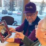 George Kudrin, left, and Pauline Golodoff hold a photo of Pauline and her late husband, Gregory Golodoff, Friday, Dec. 1, 2023, in Anchorage, Alaska. Gregory and his sister Elizabeth Golodoff Kudrin, Georges late wife, were the last two living residents of Attu, Alaska, whose entire population was captured by the Japanese during World War II and sent to Japan until being liberated after the war. The community of Attu was not rebuilt, and residents were resettled elsewhere, mostly in Atka, Alaska. (AP Photo/Mark Thiessen)