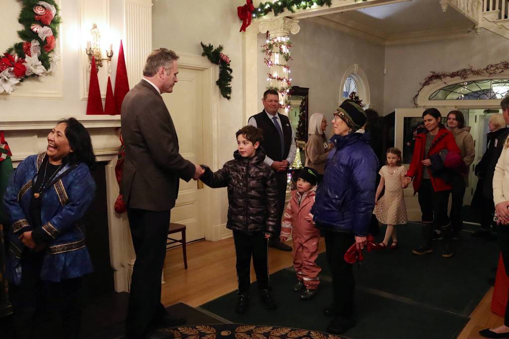 Gov. Mike Dunleavy greets Indiana Strong, 9, his sister Rozina, 4, and their grandmother Pauline during the annual Holiday Open House at the Governors Residence on Tuesday. (Mark Sabbatini / Juneau Empire)