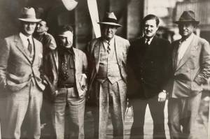 Five famous men stand together on a floatplane hangar deck on Aug. 8, 1935. From left to right: Juneau Mayor Izzy Goldstein, Pilot Wiley Post, Novelist Rex Beach, Pilot Joe Crosson, and Cowboy Philosopher Will Rogers. (Alaska State Library Ordway photo PCA-87-2631)