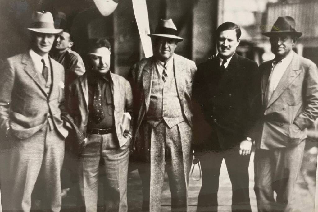 Five famous men stand together on a floatplane hangar deck on Aug. 8, 1935. From left to right: Juneau Mayor Izzy Goldstein, Pilot Wiley Post, Novelist Rex Beach, Pilot Joe Crosson, and Cowboy Philosopher Will Rogers. (Alaska State Library Ordway photo PCA-87-2631)