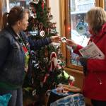 Misty Chilton (left), wife of Tlingit artist Doug Chilton, shows a Christmas ornament to Raydene Garrison at Indigenous Art Doug Chilton Designs on Monday. The downtown shop is closing on Dec. 24 as its namesake owner is planning to operate by mail order from Washington State. (Mark Sabbatini / Juneau Empire)