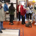 State Reps. Andi Story (foreground) and Sara Hannan, both Juneau Democrats wearing red blazers  reportedly by coincidence  greet visitors and family members during an annual holiday open house hosted by the local legislative delegation at the Alaska State Capitol on Tuesday. (Mark Sabbatini / Juneau Empire)