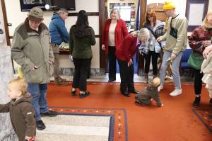State Reps. Andi Story (foreground) and Sara Hannan, both Juneau Democrats wearing red blazers  reportedly by coincidence  greet visitors and family members during an annual holiday open house hosted by the local legislative delegation at the Alaska State Capitol on Tuesday. (Mark Sabbatini / Juneau Empire)