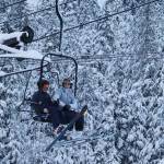 Two skiers settle into a lift chair as they pass trees with fresh snow Wednesday morning at Eaglecrest Ski Area. (Mark Sabbatini / Juneau Empire)