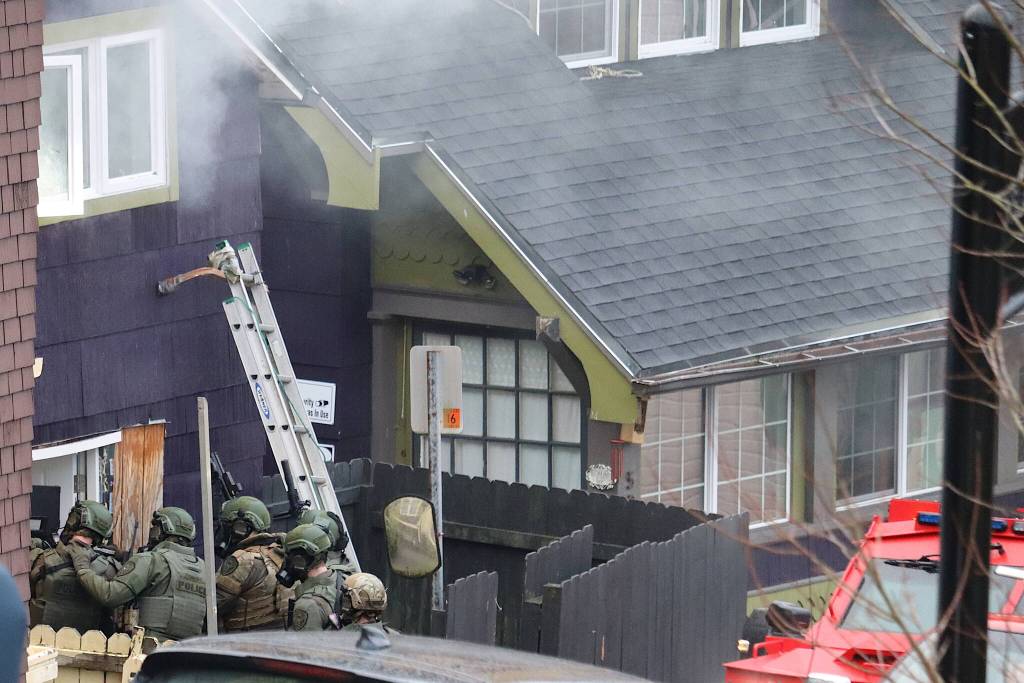 Smoke from chemical projectiles streams from the windows of a downtown residence as police enter to confront a person inside who refused to come out Thursday. (Mark Sabbatini / Juneau Empire)
