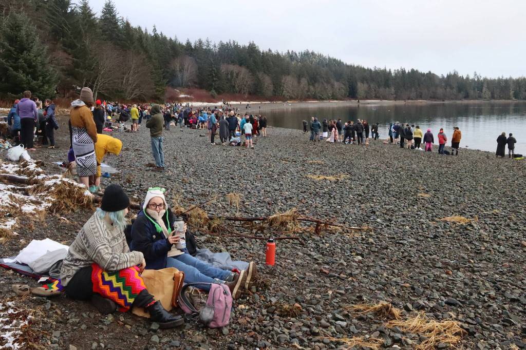Heather West (left) and Izzy Ensinger chat while bundled up on a sleeping bag minutes before taking part in the 33rd annual Juneau Polar Bear Dip at the Auke Village Recreation Area on Monday. (Mark Sabbatini / Juneau Empire)