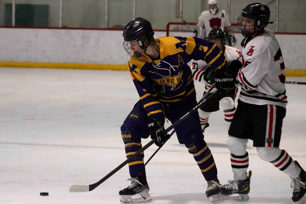 Homer High Schools Seamus Hatton (#3) tries to get the puck past Juneau-Douglas High School: Yadaa.at Kalé players during Saturdays game at Treadwell Arena. (Mark Sabbatini / Juneau Empire)