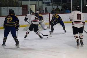 Juneau-Douglas High School: Yadaa.at Kalés Caden Morris (#15) and Sonny Monsef (#11) face off against Homer High Schools Aria Hill (#27) and Cody Thomas (#8) in front of the Homer net during Saturdays game at Treadwell Arena. (Mark Sabbatini / Juneau Empire)