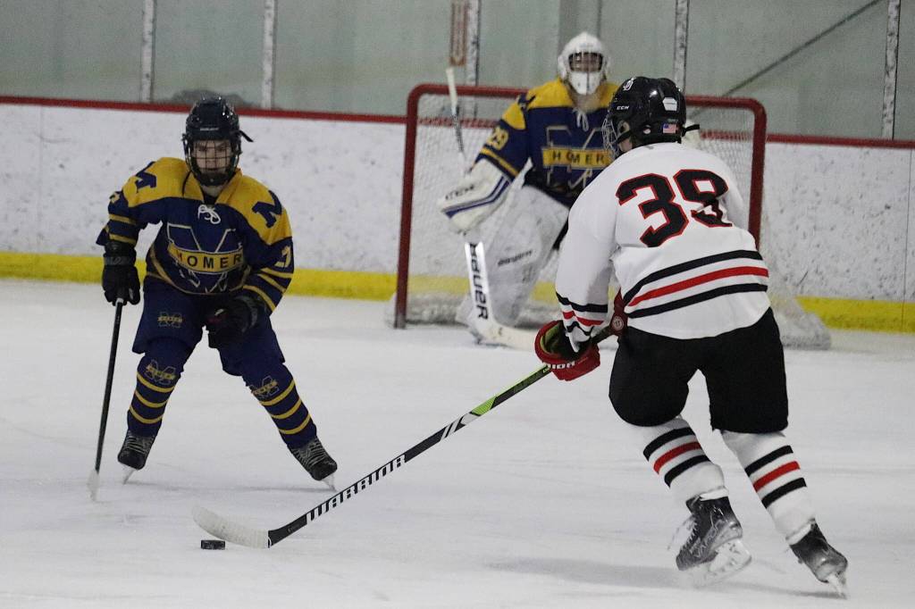 Juneau-Douglas High School: Yadaa.at Kalés Drew Cadigan-Mcadoo (#39) tries to get the puck past a smaller Homer High School player during Saturdays game at Treadwell Arena. (Mark Sabbatini / Juneau Empire)