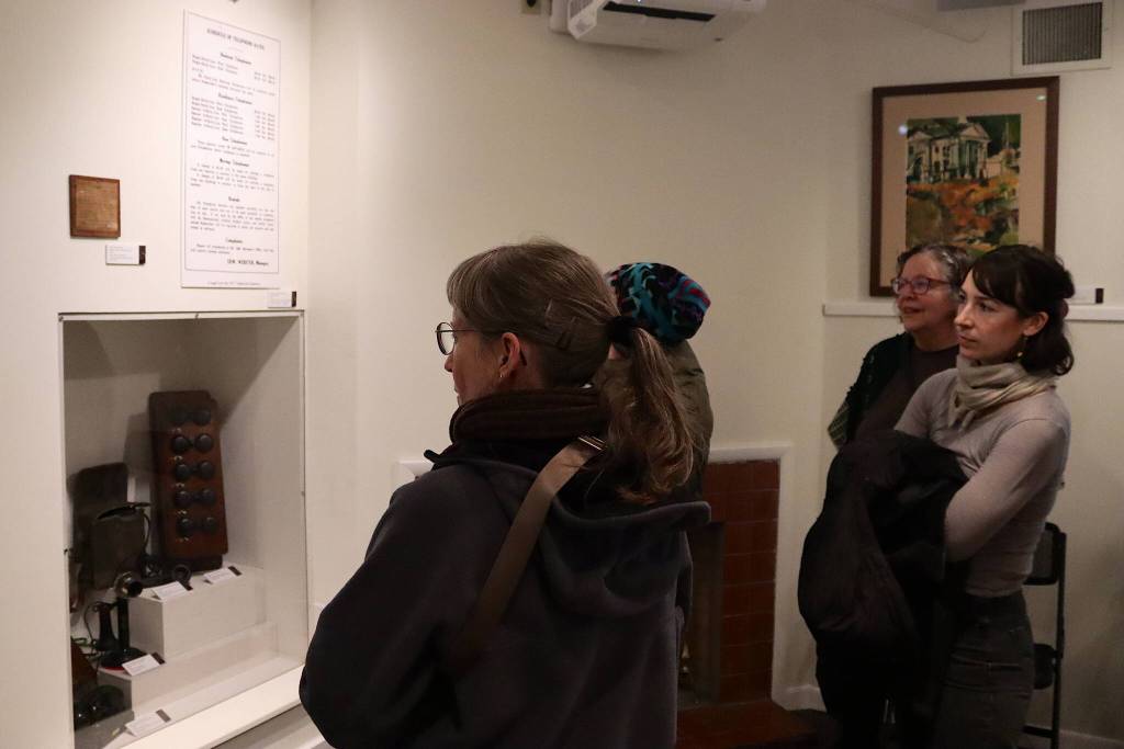 Guests at the debut of the Juneau-Douglas City Museums Switch and Exchange: A Brief History of Telephones in 20th Century Juneau examine equipment and historic displays during the exhibits opening on Friday. (Mark Sabbatini / Juneau Empire)