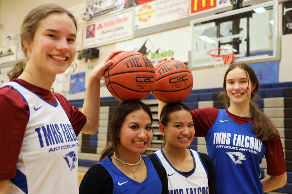 Junior twins Cailynn and Kerra Baxter, outside, and senior twins Jaya and Mikah Carandang, inside, smile for a picture after a practice last season on Feb. 2, 2023, at Thunder Mountain High School. (Clarise Larson / Juneau Empire file photo)