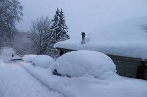 Cars parked on a hillside road near downtown are buried under heavy snow at midday Monday. (Mark Sabbatini / Juneau Empire)