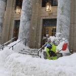Jason Skidmore shovels snow along the sidewalk in front of the Alaska State Capitol on Monday. Most legislators and staff were able to get to Juneau in time for the start of the session Tuesday. (Mark Sabbatini / Juneau Empire)