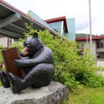 A sculpture of a bear reading a book is seen in front of Auke Bay Elementary School on July 12, 2023. The Juneau Board of Education is considering a range of drastic options, including consolidating schools, to help resolve a $9.5 million deficit this year. (Clarise Larson / Juneau Empire file photo)