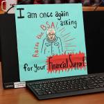 A sign propped up against a computer asks lawmakers to approve more per-student education funding during a House Rules Committee meeting Saturday. (Mark Sabbatini / Juneau Empire)