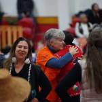 Cathy Walling of the Alaska Quaker Friends hugs Jamiann Seiltin Hasselquist in Kake, while Ati Nasiah of the non-profit Haa Tóoch Lichéesh smiles in the foreground on Jan. 19. (Photo by Shaelene Grace Moler)