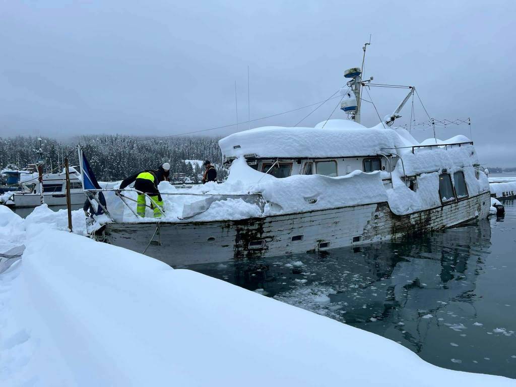 Local harbor workers clear snow from a boat in danger of sinking this week due to record snowfall. While boat owners are responsible for clearing their own vessels, city workers are forced to do so if a sinking poses environmental or other public safety hazards. (City and Borough of Juneau photo)