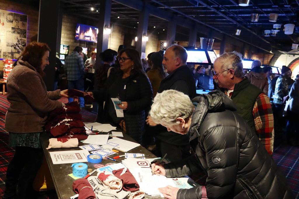 Supporters of U.S. Rep. Mary Peltola sign registration sheets and pick up campaign gear during a meet-and-greet Saturday evening at the Crystal Saloon. (Mark Sabbatini / Juneau Empire)