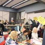 Juneau School District leaders hold up signs for subgroups they are leading during a Community Budget Input Session at Thunder Mountain High School on Wednesday night. (Mark Sabbatini / Juneau Empire)