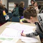 Amanda Babin, a former paraeducator and parent of a child entering kindergarten soon, writes down her preference among five consolidation options currently being considered by the Juneau School District during a meeting Wednesday night at Thunder Mountain High School. (Mark Sabbatini / Juneau Empire)