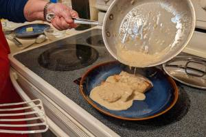 Pouring sauce over finished rockfish. (Photo by Patricia Schied)