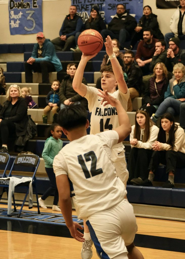 Thunder Mountain senior Samuel Lockhart (14) shoots from the arc as sophomore Joren Gasga signals a three during the Falcons 71-49 win over the Bears, Thursday at the Thunderdome. (Klas Stolpe / For the Juneau Empire)