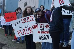 Juneau-Douglas High School: Yadaa.at Kalé students hold up signs during a rally along Egan Drive on Tuesday afternoon protesting a proposal to consolidate all local students in grades 10-12 at Thunder Mountain High School to help deal with the Juneau School Districts financial crisis. (Mark Sabbatini / Juneau Empire)