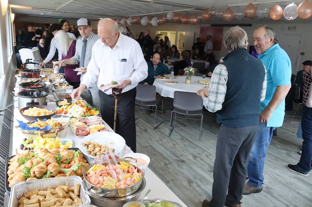 Guests at Jirdes Winther Baxters 100th birthday party help themselves to the buffet at the Juneau Yacht Club on Saturday. (Mark Sabbatini / Juneau Empire)