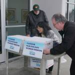 Former state labor commissioner Ed Flanagan, State Rep. Genevieve Mina, D-Anchorage, and the Rev. Michael Burke of St. Marys Episcopal Church in Anchorage wheel boxes of signed petitions into a state Division of Elections office on Jan. 9. The petitions were for a ballot initiative to increase the states minimum wage, mandate paid sick leave and ensure that workers are not required to hear employers political or religious messages. (Photo by Yereth Rosen/Alaska Beacon)