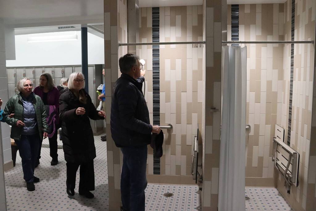 Andy Hemenway, a longtime Juneau resident, inspects new individual showers in the mens locker room at the renovated Augustus G. Brown Swimming Pool during Fridays ribbon-cutting ceremony. (Mark Sabbatini / Juneau Empire)