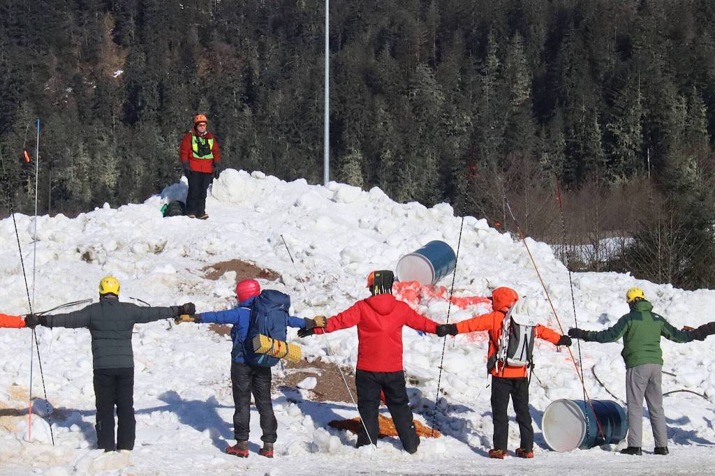 Rescuers line up at arms length before starting to probe a snow hill for victims of a simulated avalanche on Saturday in Lemon Creek. (Mark Sabbatini / Juneau Empire)