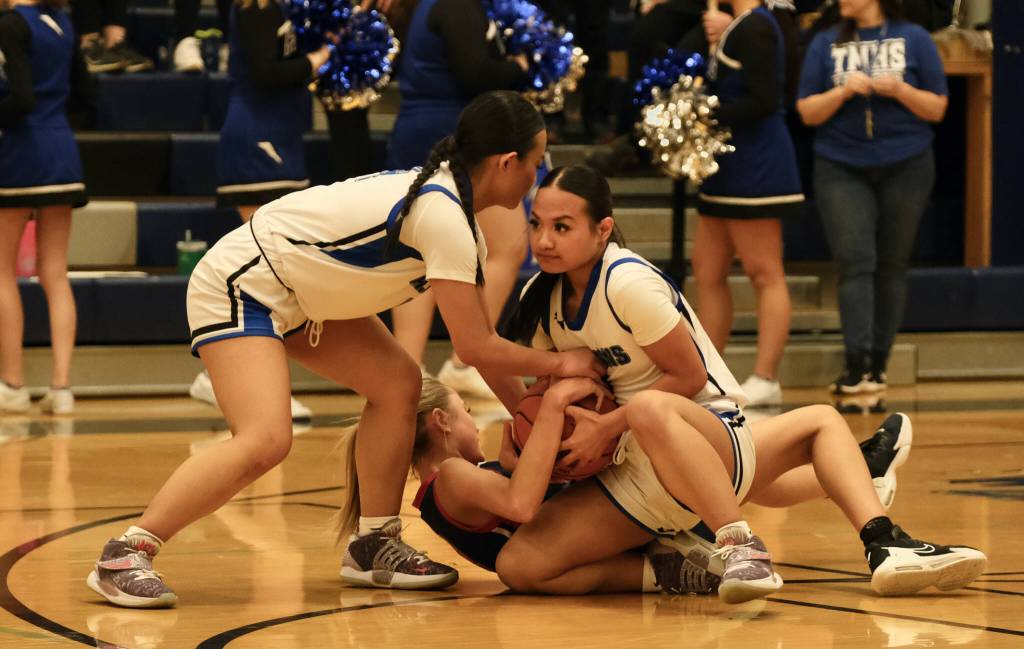 Thunder Mountain High School seniors Mikah Carandang, left, and Jaya Carandang, right, battle for a loose ball with North Poles Tiahna Guzman during the Falcons 36-31 win over the Patriots on Saturday at the Thunderdome. (Klas Stolpe / For the Juneau Empire)