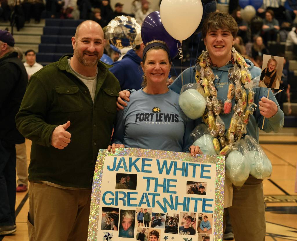 Thunder Mountain High School pep band senior Jake White, at right, stands with parents Steve and Kerri during Saturday Falcons senior night honors. (Klas Stolpe / For the Juneau Empire)