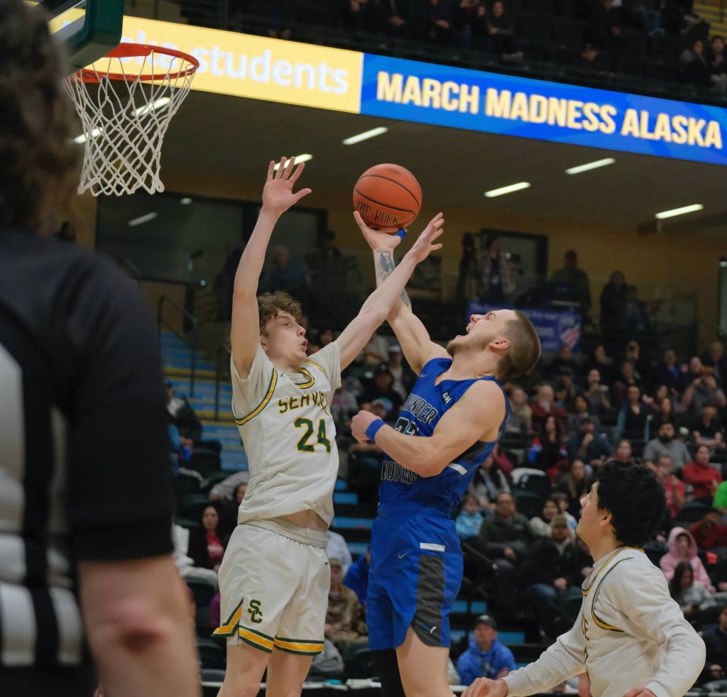 Thunder Mountain senior Thomas Baxter (33) is hit on a shot by Service sophomore Leyton Lockard (24) during the Falcons 48-45 overtime win against the Cougars in a semifinal at the 2024 ASAA March Madness Alaska 4A Boys Basketball State Championships on Friday at Anchorages Alaska Airlines Center. (Klas Stolpe / For the Juneau Empire)