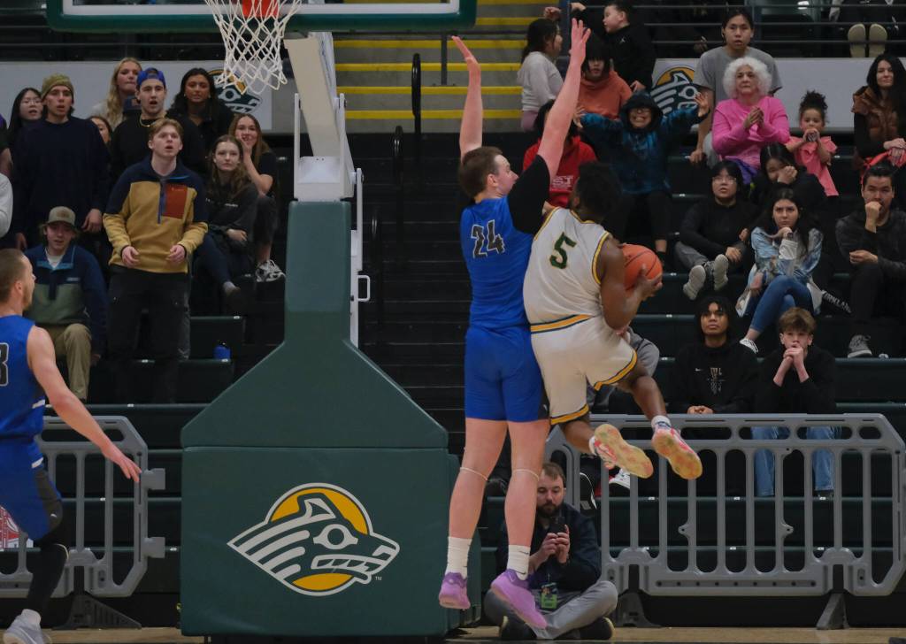 Thunder Mountain senior James Polasky (24) blocks a last second shot attempt by Service senior Mackeenan Morgan (5) during the Falcons 48-45 overtime win against the Cougars in a semifinal at the 2024 ASAA March Madness Alaska 4A Boys Basketball State Championships on Friday at Anchorages Alaska Airlines Center. (Klas Stolpe / For the Juneau Empire)