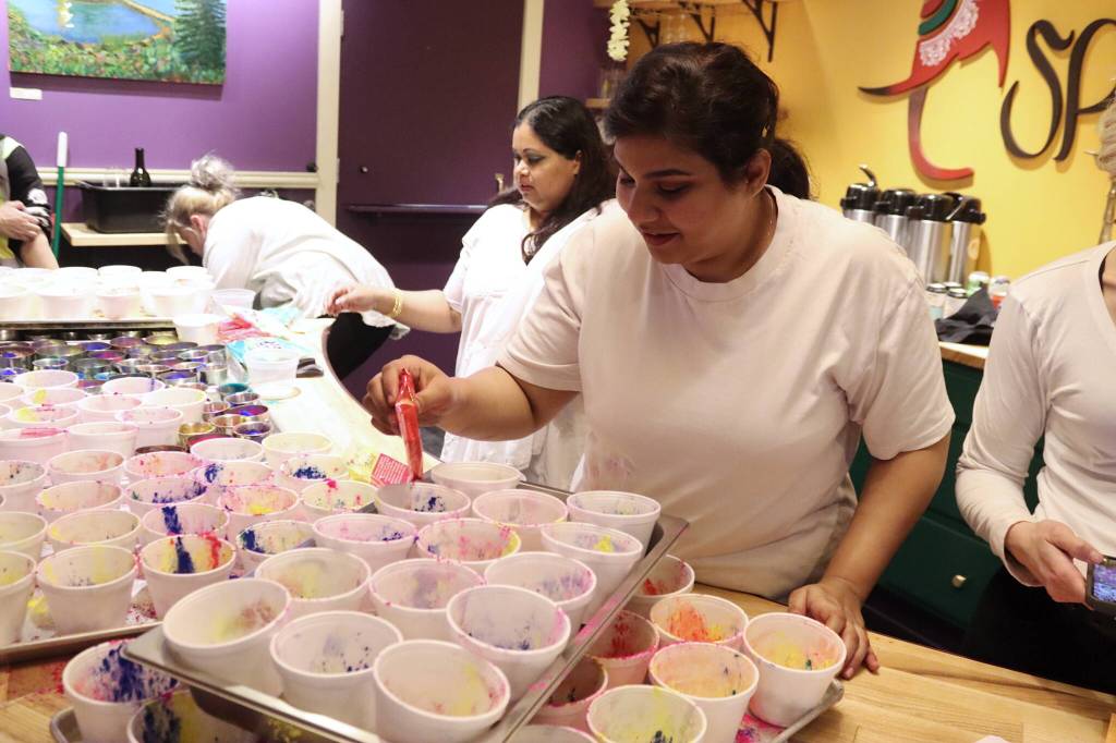Ruth Fisher, an employee at Spice Juneau Indian Cuisine, fills cups with colored cornstarch shortly before the throwing of colors outside as part of a Holi festival Monday night. (Mark Sabbatini / Juneau Empire)
