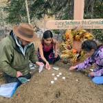 In this Sept. 29, 2023, photo at the grave of Lucky Pitka McCormick, her granddaughter Kathleen Carlo, left, and McCormicks great-great-grandchildren Lucia, center, and Addison Carlo place candles and stones on the grave during a reburial ceremony in Rampart, Alaska. Pitka was one of the Lost Alaskans sent to a mental hospital in the 1930s. Her grave was recently discovered, and family members brought her back to Alaska for a proper burial. (Wally Carlo via AP).