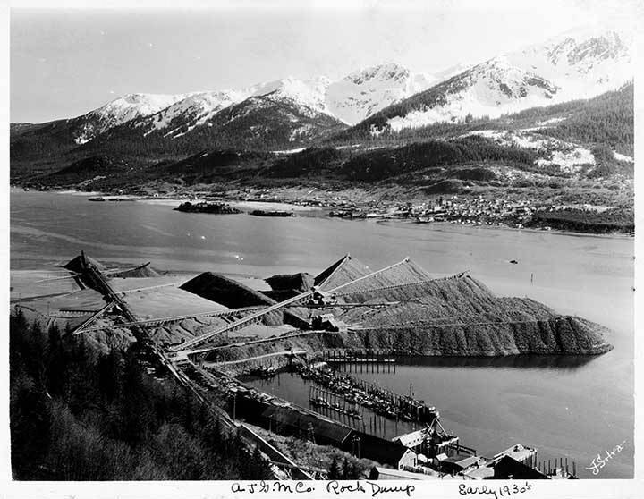 Looking over the distribution patterns of waste rock that created the rock dump in the early 1930s. The photo was taken from the A-J mill building with Douglas Island in the distance. (ASL-01-2036)