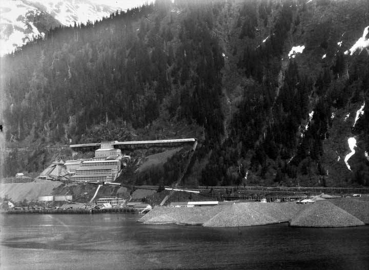 View from Gastineau Channel looking at the Alaska-Juneau Gold Mines ore processing mill on the side of Mount Roberts. Waste rock from the mine was deposited into the channel by rail and conveyor belts in broad fingers of material to form the rock dump. (ASL-M999-A-J-MILL-001)