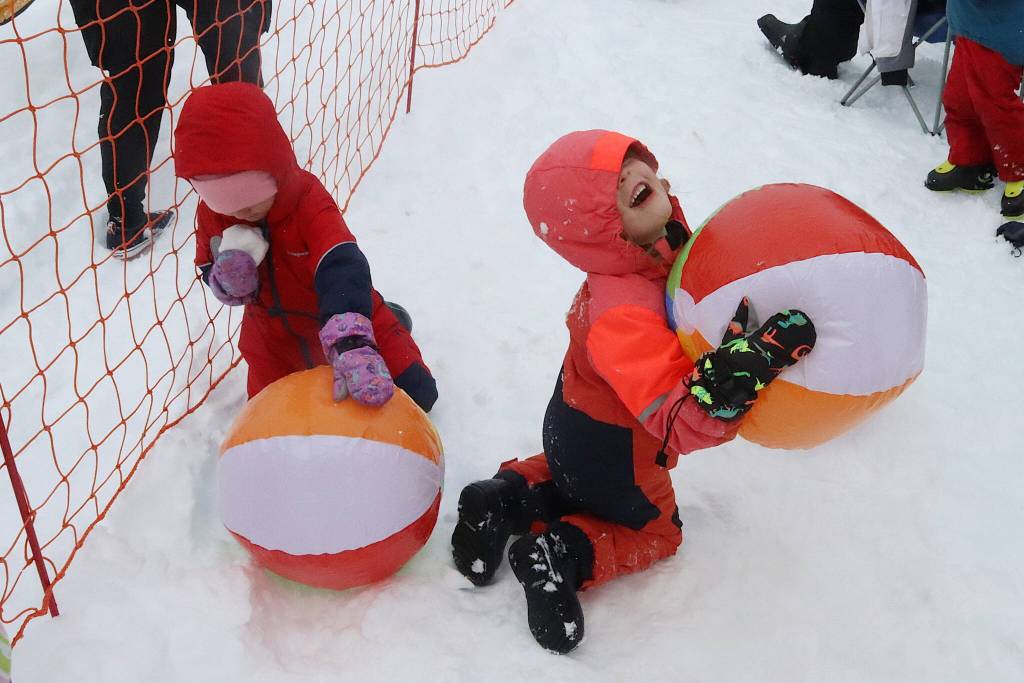Adalee DiMarzio clutches a beach ball while her brother, Bryer, contemplates a chunk of snow as well as a ball during the Slush Cups beach party on Sunday at Eaglecrest Ski Area. (Mark Sabbatini / Juneau Empire)