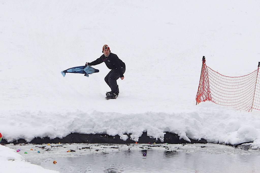 Charles Gueriera tries to cross the pond at the Slush Cup with Tango Two, a stuffed whale named after a humpback whale calf that died last summer after apparently being hit by a large boat, during the last day of the season at Eaglecrest Ski Area on Sunday. (Mark Sabbatini / Juneau Empire)