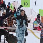 Craig Brown (left), Mia Holloway, 8, and Swanee Bure, 9, reveal scorecards for Michael Dale, the overall winner of this years Slush Cup after he performed a 180-degree turn at the beginning of his crossing of the 100-foot-long pond at Eaglecrest Ski Area on Sunday. (Mark Sabbatini / Juneau Empire)