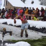 Colton Johns wades to shore in his beachwear after falling into the water during the Slush Cup at Eaglecrest Ski Area on Sunday. (Mark Sabbatini / Juneau Empire)