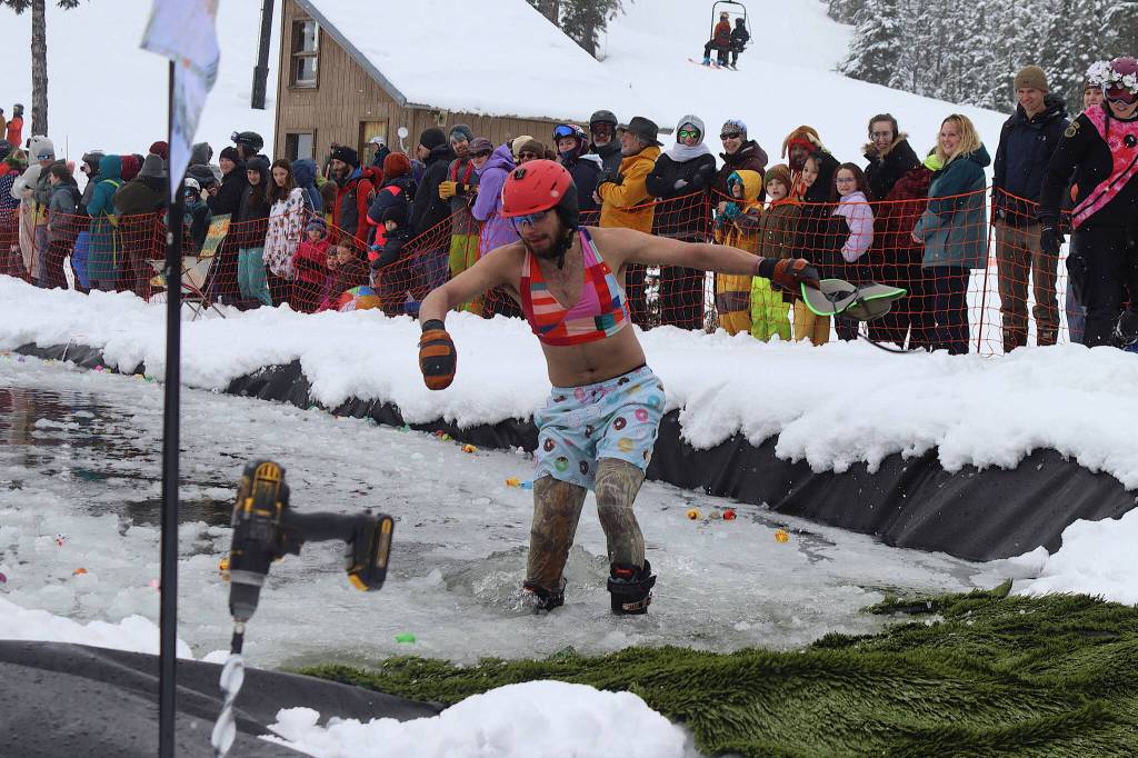 Colton Johns wades to shore in his beachwear after falling into the water during the Slush Cup at Eaglecrest Ski Area on Sunday. (Mark Sabbatini / Juneau Empire)