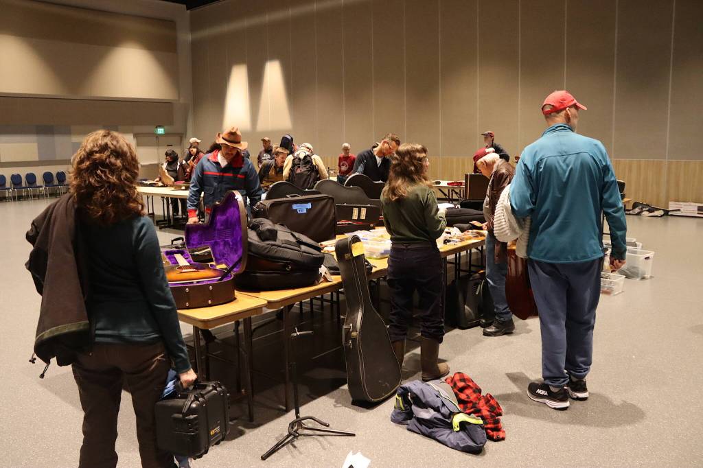 Buyers and sellers exchange words and equipment during an instrument swap at Centennial Hall on Sunday as part of the Alaska Folk Festival. (Mark Sabbatini / Juneau Empire)