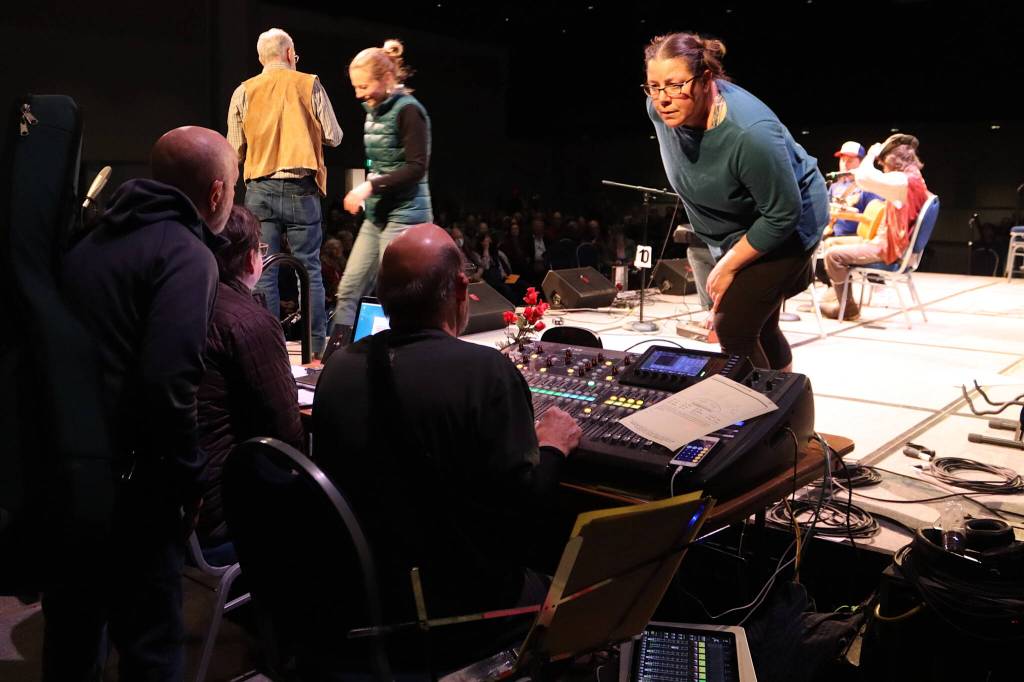 Kayla Boettcher, a member of the technical crew for the Alaska Folk Festival, checks with sound engineers as musicians set up for their performance on Sunday night at Centennial Hall. (Mark Sabbatini / Juneau Empire)
